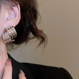 Close-up of textured silver C-shaped earrings worn by a model in a fashion setting