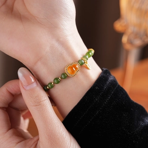 Detail of beaded gourd bracelet featuring orange garnet and green jasper beads on wrist
