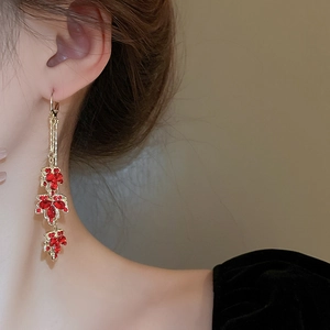 Gros plan de boucles d'oreilles pampilles feuille d'érable rouge avec strass brillants