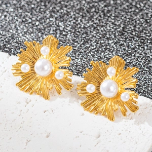 Détails macro de boucles d'oreilles cœur dorées 18k avec perles sur fond texturé chic