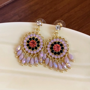 Macro view of vintage gold earrings with red zircon, purple beads and fringe tassels