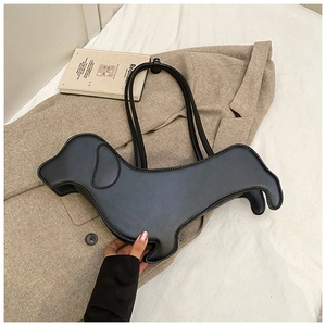 Detailed view of a black dachshund-shaped shoulder bag resting on a beige blazer and white sheets