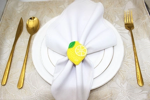 Detail of a bright lemon napkin ring on a white linen napkin for outdoor dining