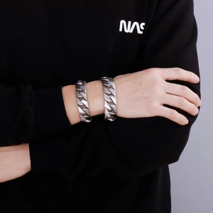Close-up of stacked silver Cuban link bracelets in polished and matte finish on a wrist