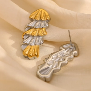 Dual-tone gold and silver layered Christmas tree style earrings on beige silk backdrop