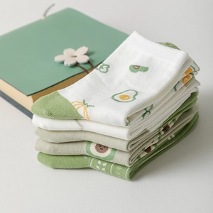 Green and white mid-calf cotton socks with cute avocado embroidery in lifestyle setting