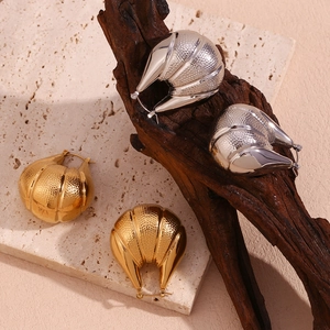 Detail of 18K gold and silver peanut-shaped C-style earrings with hammered metal texture