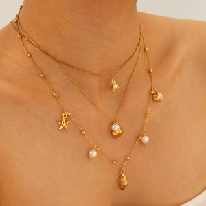Three-layer gold starfish shell pearl pendant necklace elegantly worn by a model
