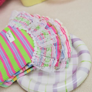 Close-up of knit pet dress with colorful stripes and delicate white lace trim details