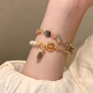 Detail of layered bracelet set with irregular pearls, orange gems and agate beads
