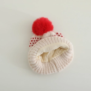 Détail du bonnet en tricot beige pour bébé avec motifs cœurs rouges et doublure douce