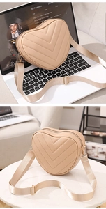 Macro shot of heart-shaped beige crossbody bag with V-quilt pattern and gold hardware
