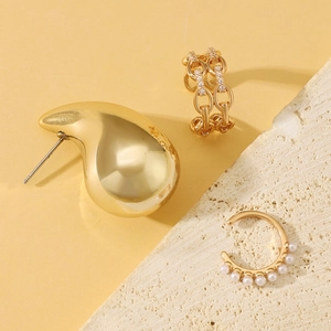 Detailed view of elegant gold-plated ear cuffs with zircon stones and pearls on stone props