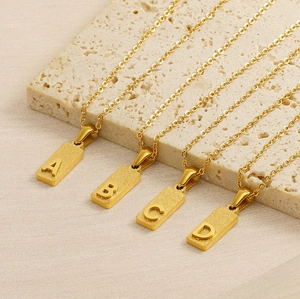 Detailed shot of letters A, B, C, D on matte gold square pendants with O-chain