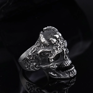 Detail of vintage silver skull ring with intricate gothic carving on black background