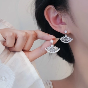 Detail shot of fan-shaped silver earrings with cubic zirconia worn by a model