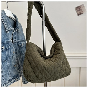 Detail of army green corduroy tote bag with diamond quilting hanging on a silver hanger