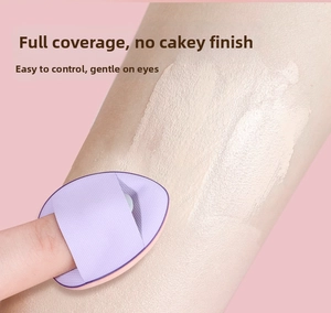 Detail of purple finger concealer puff applying foundation on under-eye area smoothly