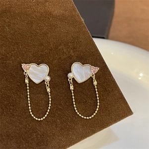 Close-up of heart-shaped earrings with white mother-of-pearl and pink zircon detailing