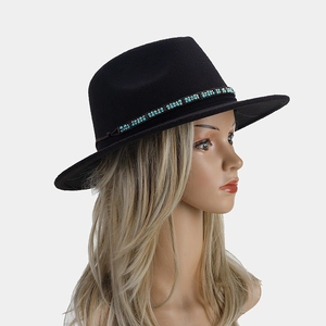 Détail d'un chapeau fedora noir avec une bande de perles turquoise sur feutre de laine