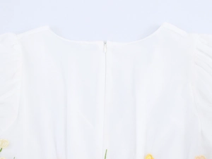 Détail du dos de la robe blanche en tulle avec zip invisible et broderie florale jaune