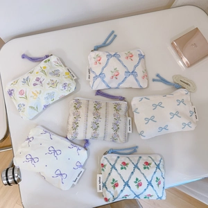 Flat lay of floral cotton coin purses with bows and zippers in blue and purple tones