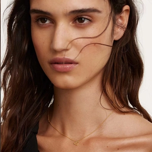 Detailed close-up of a model wearing the gold heart pendant necklace on a fine chain