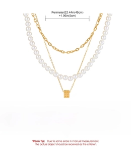 Detail view of multi-layered gold alloy necklace with white pearls and dice charm