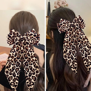 Detailed view of elegant leopard print bow hair clip with long ribbons on model