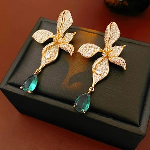 Detail of vintage gold butterfly earrings with emerald teardrop stones on black display