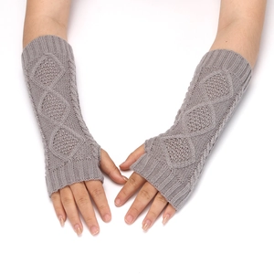 Detail view of gray knitted fingerless gloves on a model with a focus on woven texture