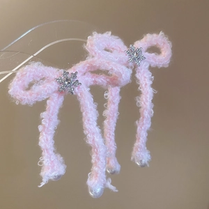 Close-up of pink fuzzy bow earrings with silver snowflake charms and white pearl drops