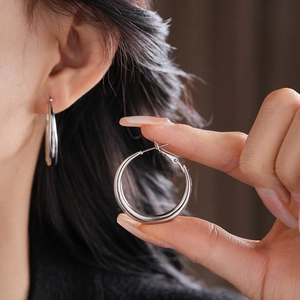 Close-up of chunky silver hoop earrings with a gradient streamlined metal design