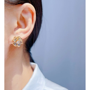 Blue crystal flower stud earrings in gold with zircon petals worn by a model