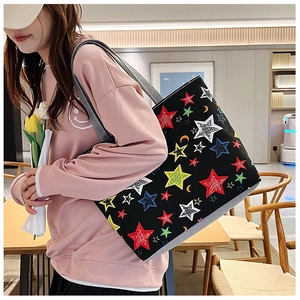 Detailed view of canvas tote bag with colorful stars and moons print worn with pink hoodie