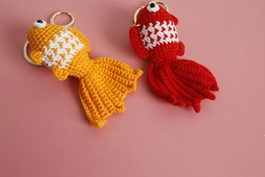 Macro shot of handmade crochet goldfish keychains in red and yellow wool with metal rings