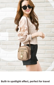 Detailed view of khaki leather mini backpack with multiple zippers and golden cat charm