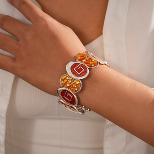Detail of bohemian enamel bangle with orange red geometric patterns and silver stars