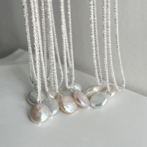 Macro detail of iridescent baroque coin pearls on a shimmering S925 sterling silver chain
