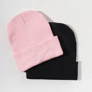 Close-up of pink and black knit beanies with ribbed texture for winter warmth