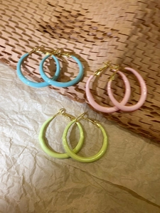 Three pairs of large enamel circle earrings in blue, pink, and light green pastel tones