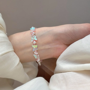 Detail of beaded bracelet featuring iridescent butterfly pendants and white faux pearls