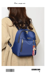Detail view of a blue nylon backpack with gold zippers and a cute brown bear charm