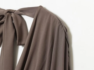 Detail of silk-like V-neck dress showing the bow-tie knot and smooth shoulder texture