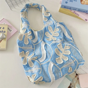 Détail du sac fourre-tout en tissu bleu clair avec broderie dentelle et franges