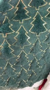 Close-up of deep green plush fabric with gold sequin embroidered Christmas tree pattern