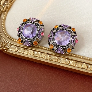 Close-up of vintage silver earrings with purple center stone and colorful rhinestones