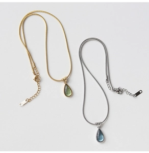 Close-up of teardrop pendant snake chains in gold and silver with K18 engraving
