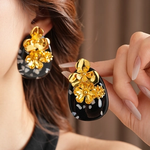 Detail of vintage metal flower earrings with black resin base and gold floral design