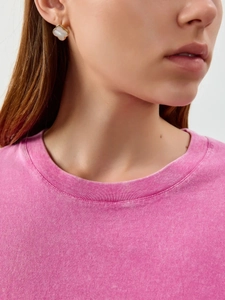 Close-up of pink washed cotton t-shirt collar with gold-rimmed clover earrings detail